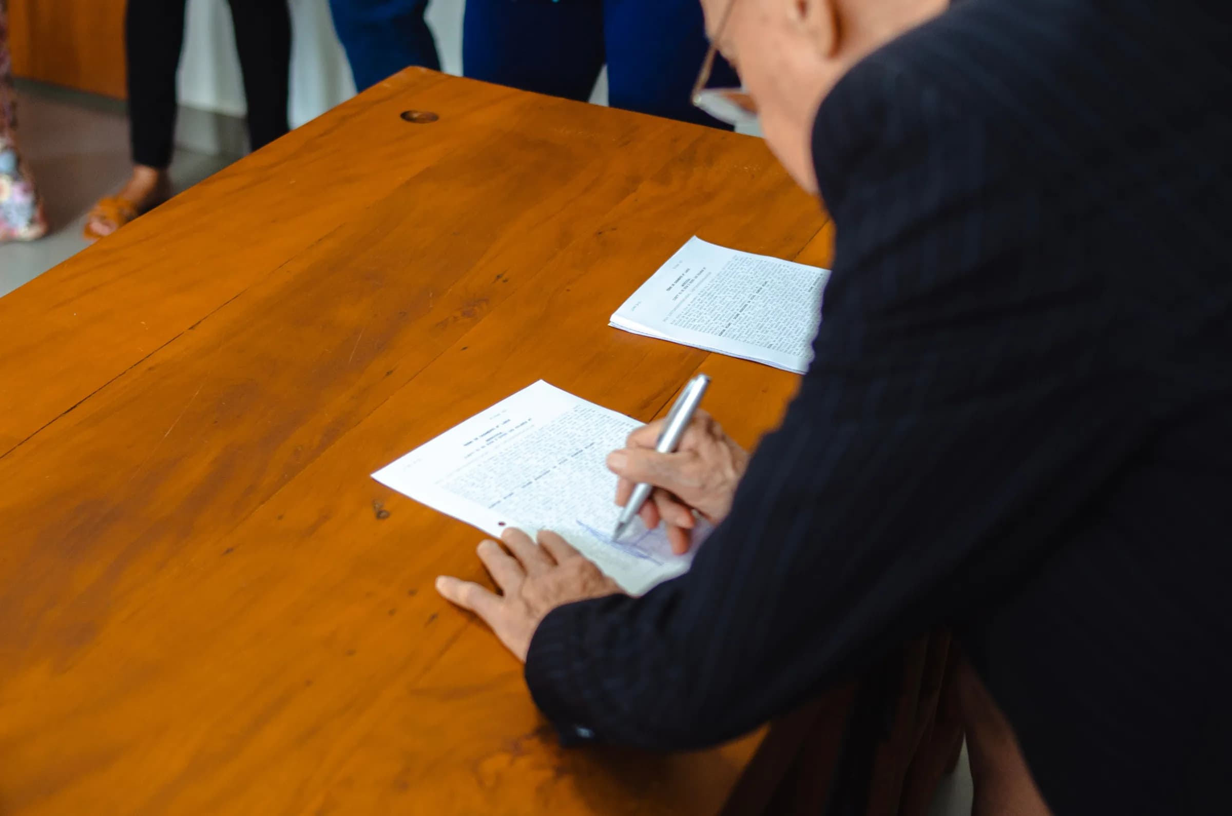 Personne signant un document lors d’une réunion autour d’une table