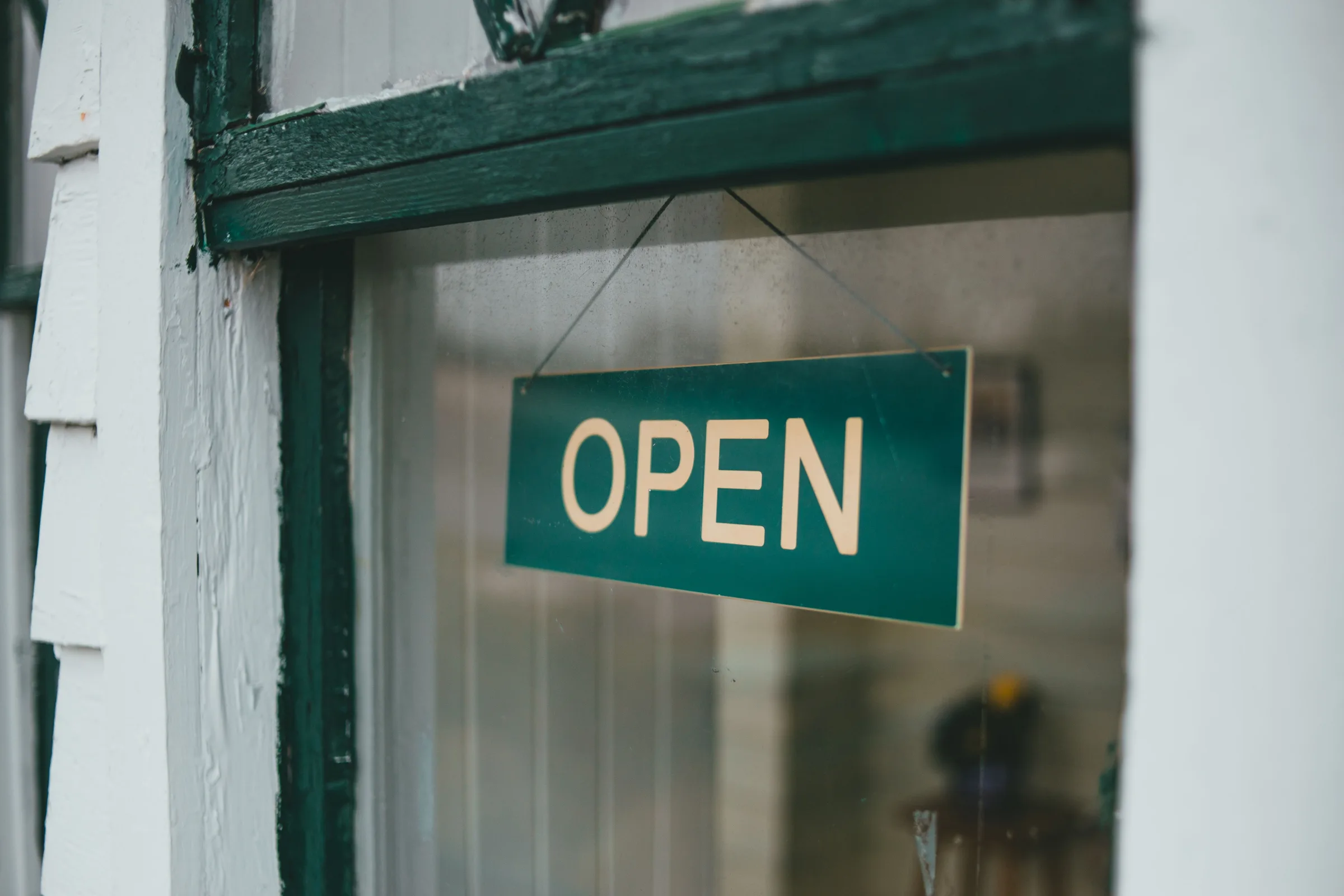 Panneau « Open » à l’entrée d’un commerce, illustrant l’ouverture d’un établissement